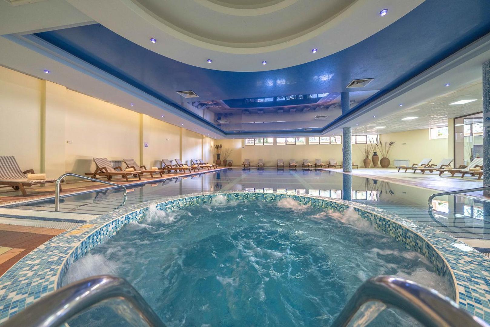 Grifid Club Hotel Bolero iekštelpu baseins ar džakuzi zonu un atpūtas krēsliem — plaša spa zona relaksācijai Zelta smiltīs, Bulgārijā