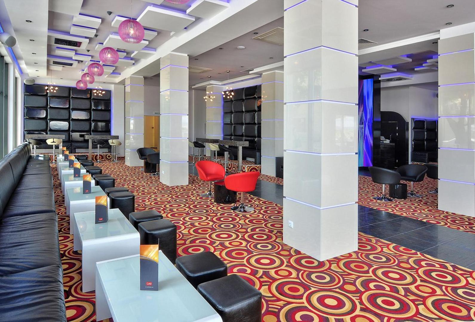 GRIFID Metropol Hotel modernais lobby bārs ar krāsainu paklāju, dizaina apgaismojumu un ērtām atpūtas zonām viesnīcas iekštelpās