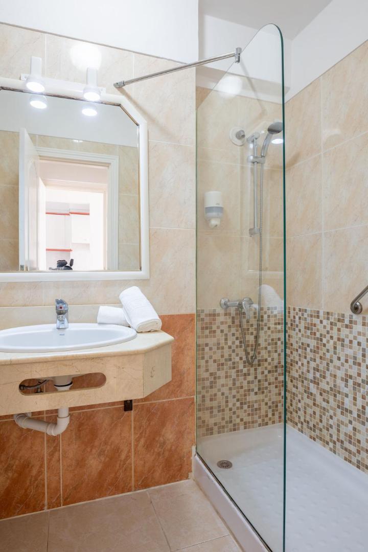 Villa De Adeje Beach viesnīcas numura vannas istaba ar dušas kabīni, spoguli un gaišām flīzēm Tenerifes kūrortā