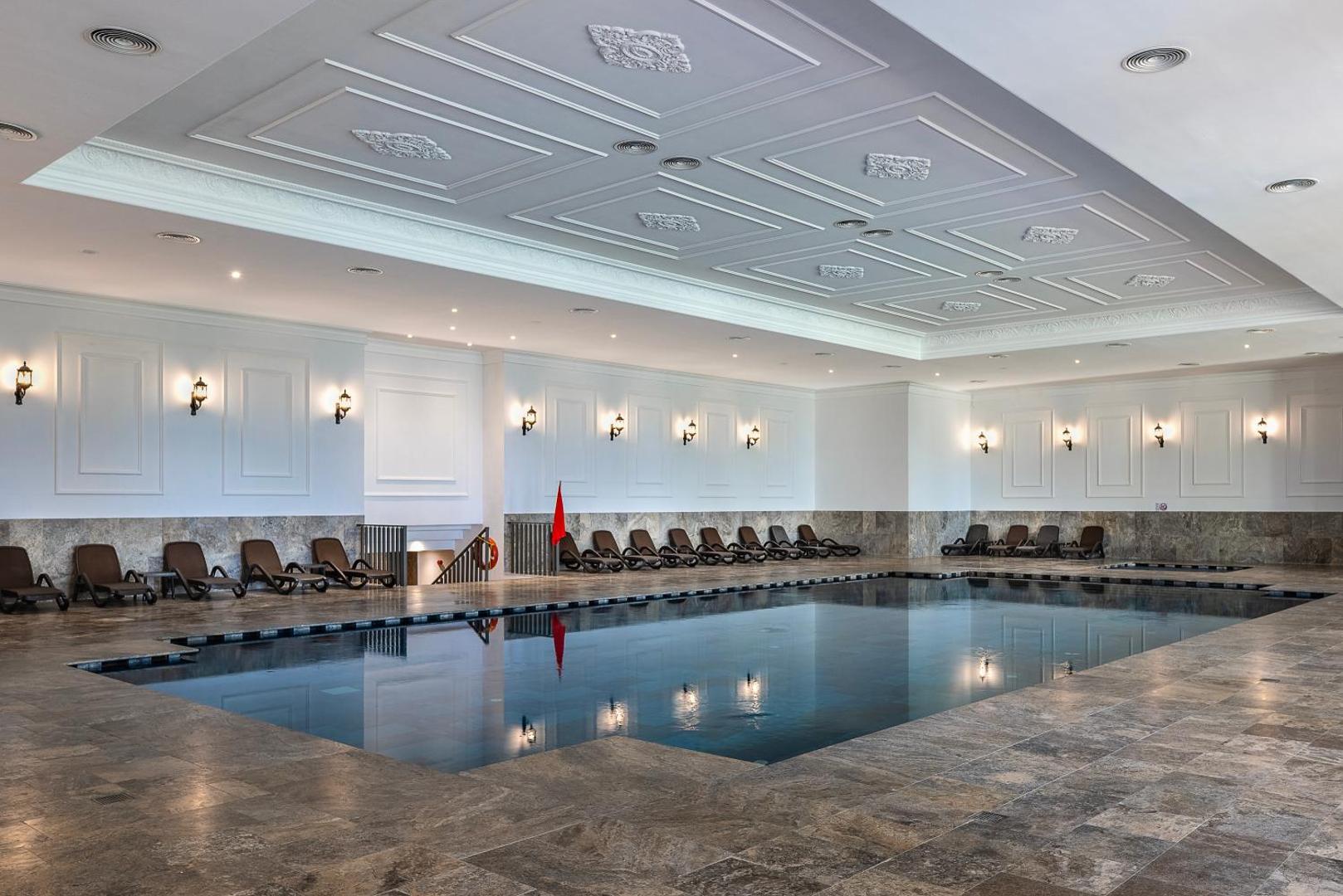 Adora Hotel & Resort iekštelpu baseins ar apsildi, atpūtas krēsliem un klasisku interjera dizainu spa zonā