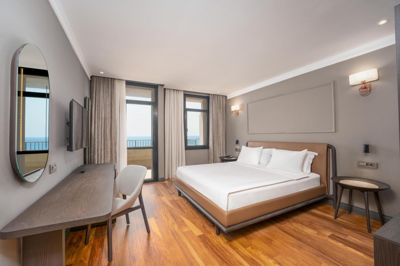Adora Hotel & Resort numurs ar koka grīdu, plašu gultu un balkonu ar skatu uz jūru Antaljas kūrortā