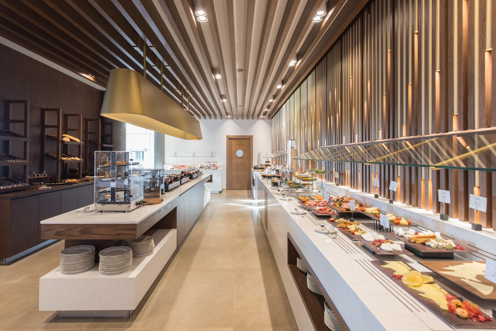 Nana Princess Suites Villas & Spa restorāna bufetes zona ar plašu uzkodu izvēli, sieriem un svaigu maizi modernā interjerā Hersonisā