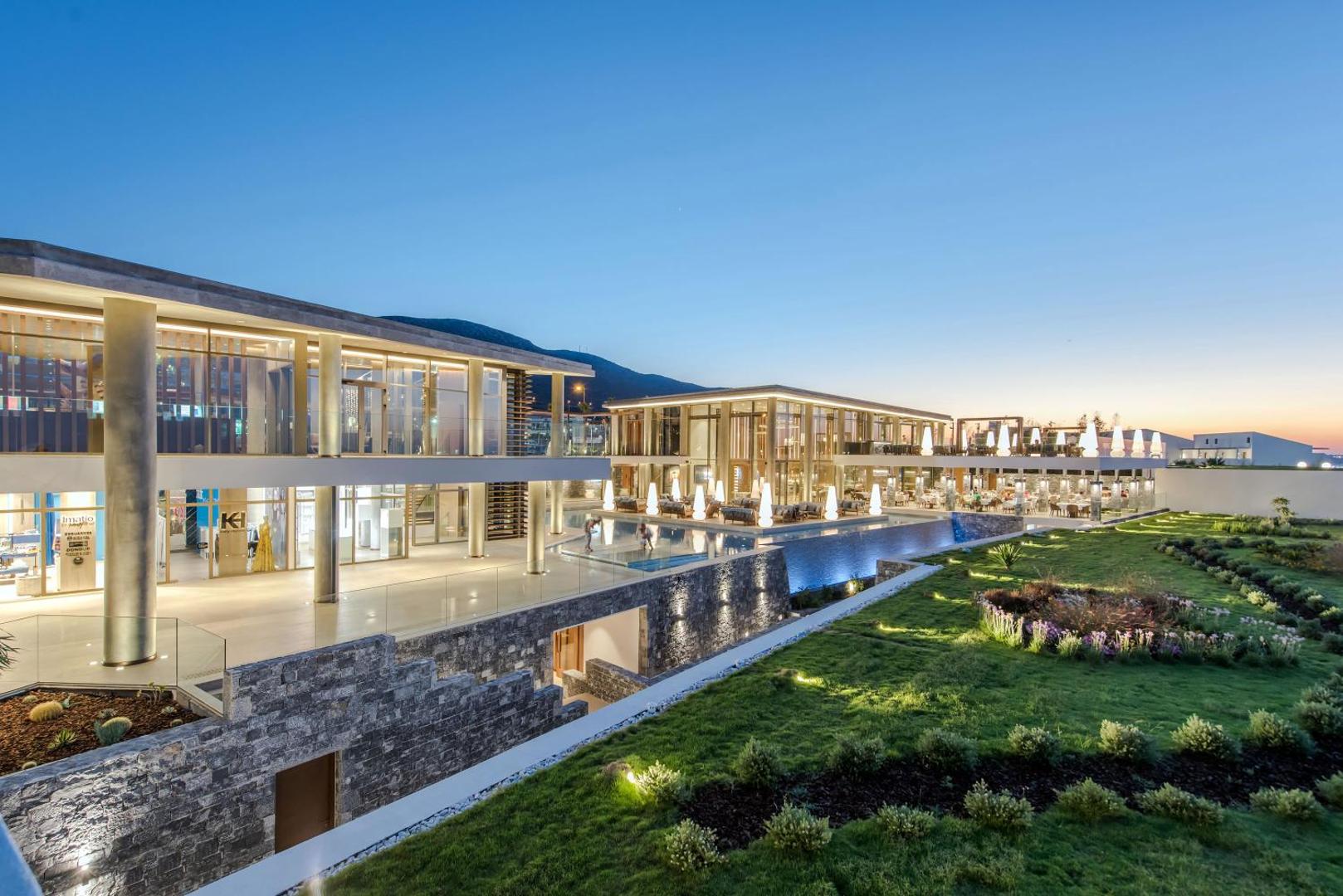 Nana Princess Suites Villas & Spa modernā arhitektūra un apzaļumotā teritorija vakarā — skats uz viesnīcas korpusiem un dārzu