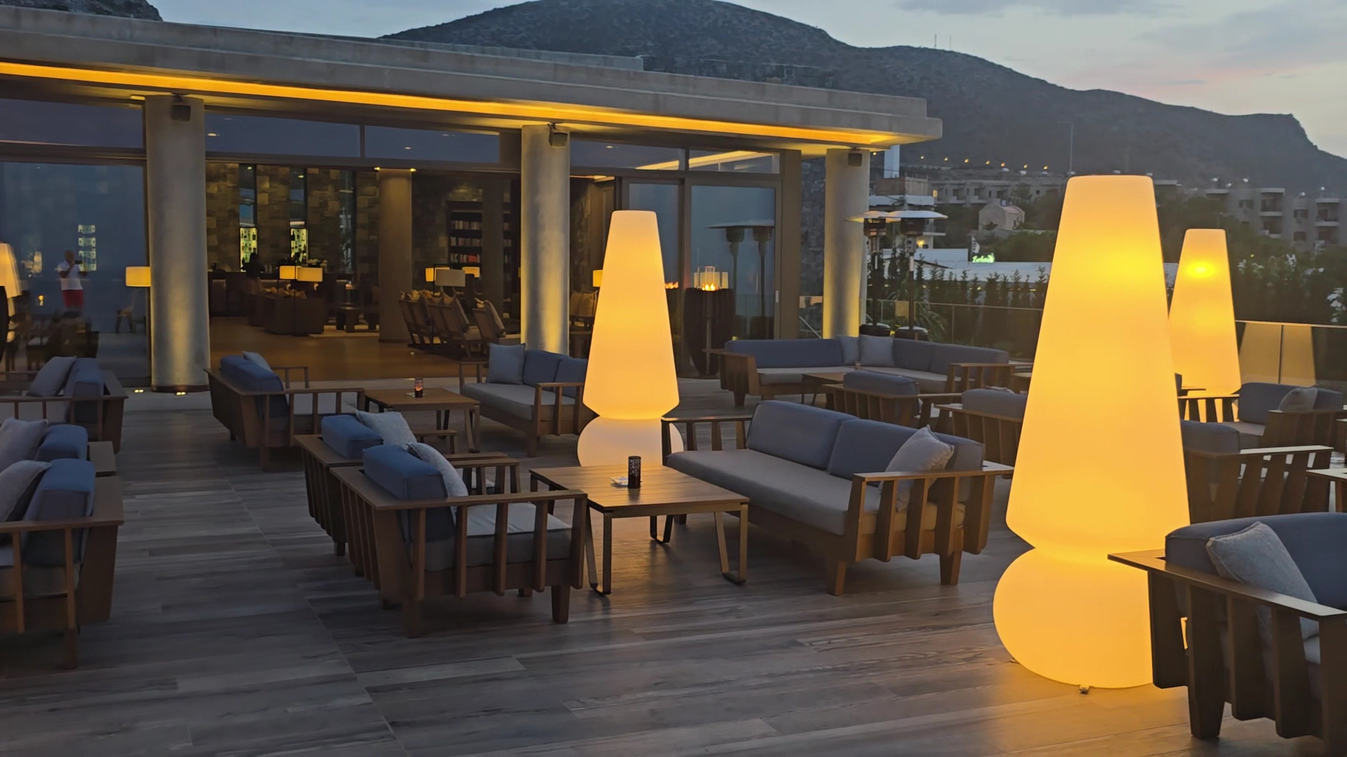 Nana Princess Suites Villas & Spa āra terase vakarā ar stilīgiem gaismas ķermeņiem, mīkstajām mēbelēm un skatu uz kalniem