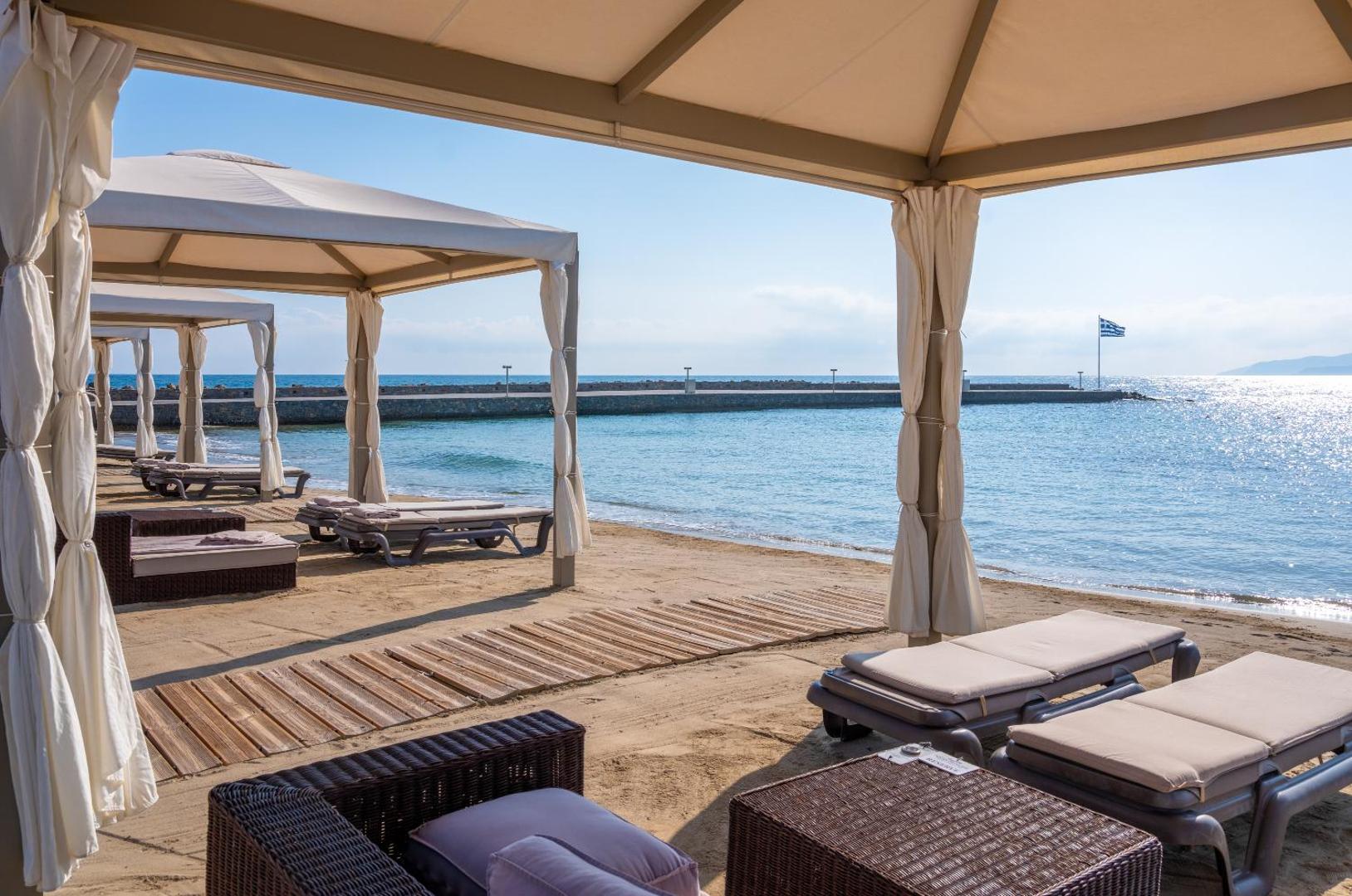 Nana Princess Suites Villas & Spa pludmales nojumes ar mīkstiem zviļņiem un skatu uz jūras piestātni saulainā dienā