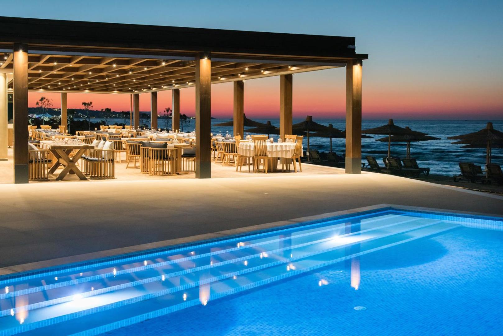 Nana Princess Suites Villas & Spa ēdienkartes restorāns ar āra terasi vakara gaismās blakus izgaismotam baseinam un jūrai