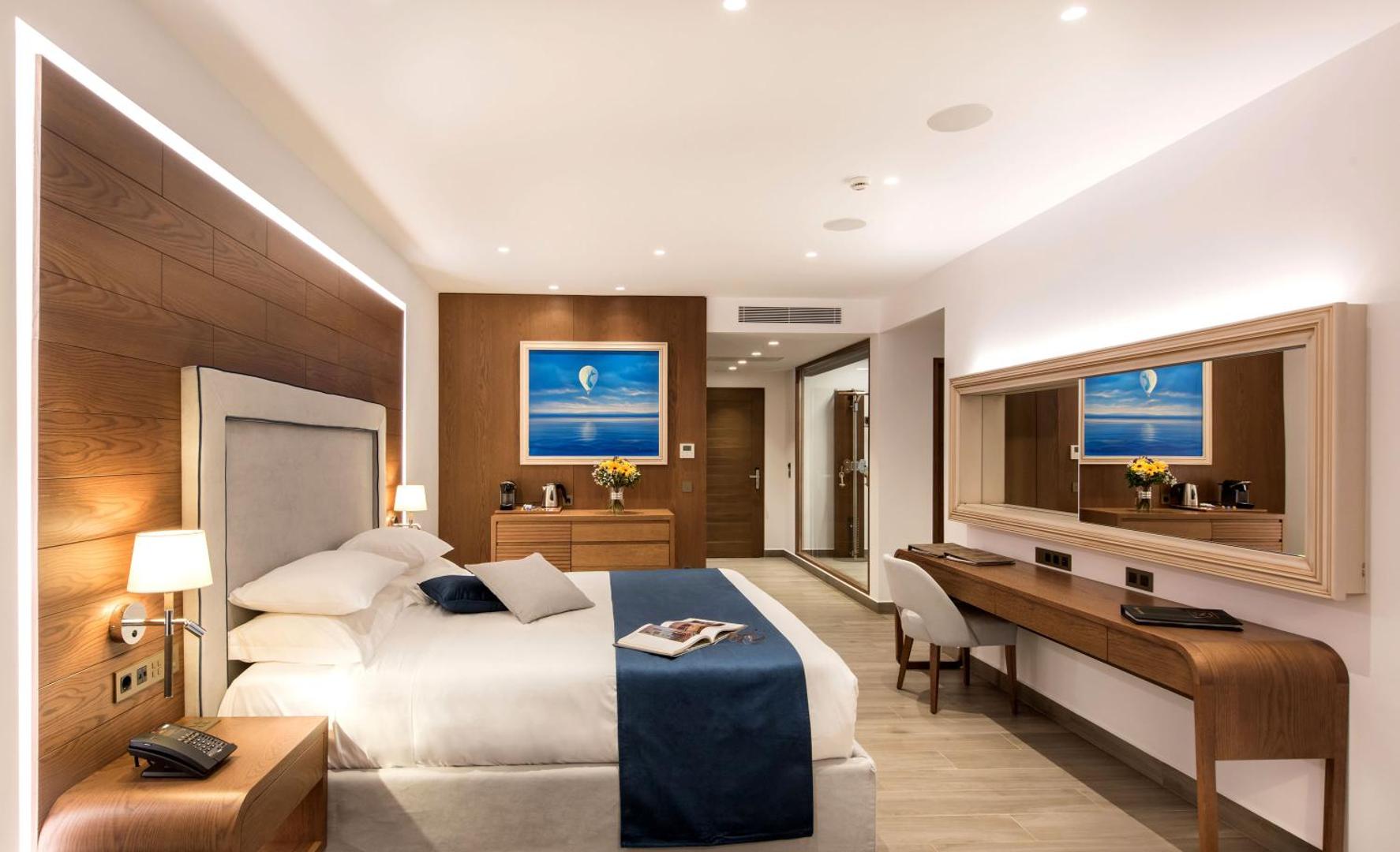 Nana Princess Suites Villas & Spa moderns numurs ar koka apdari, lielu spoguli un ziliem akcentiem Hersonisā, Krētā