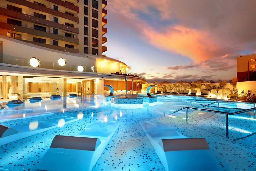 Hard Rock Hotel Tenerife izgaismots spa baseins vakarā ar masāžas strūklām un modernu arhitektūru saulrieta laikā
