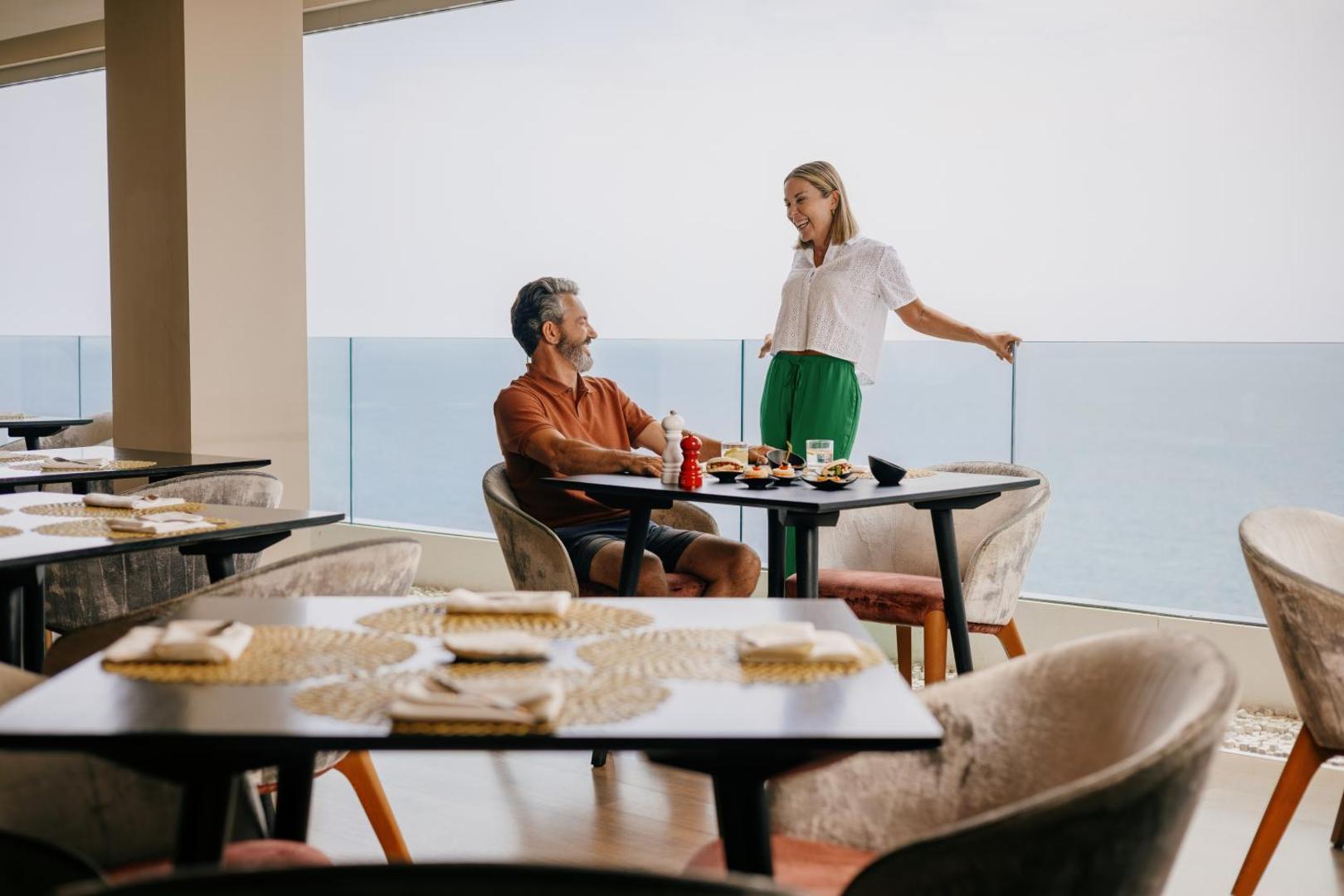 Pāris bauda pusdienas Hard Rock Hotel Tenerife terases restorānā ar skatu uz Atlantijas okeānu Kanāriju salās.