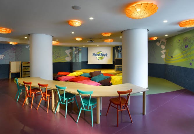 Hard Rock Hotel Tenerife bērnu kluba telpa ar krāsainiem sēžammaisiem, radošo galdu un zīmējumiem uz sienām bērnu izklaidei.