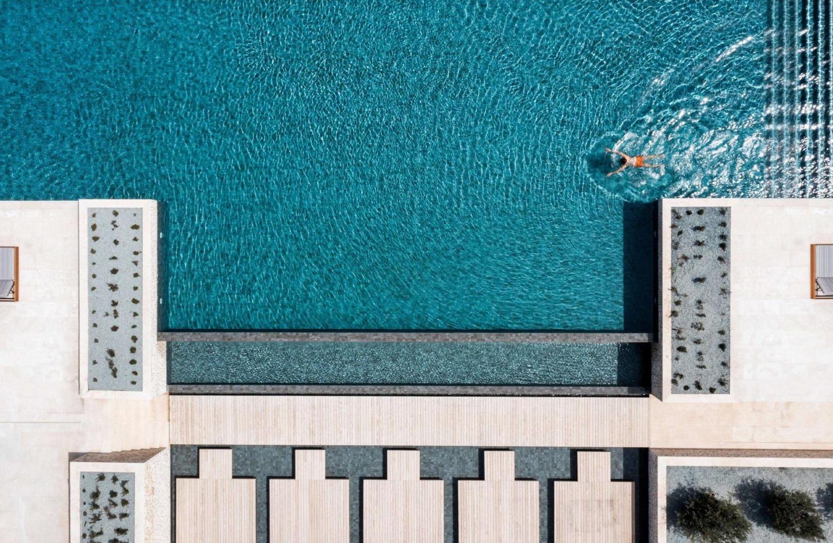 Cap St Georges Hotel & Resort skats no augšas uz galveno baseinu un sauļošanās zonu Pafas reģionā, Kiprā — moderns dizains un tirkīzzils ūdens