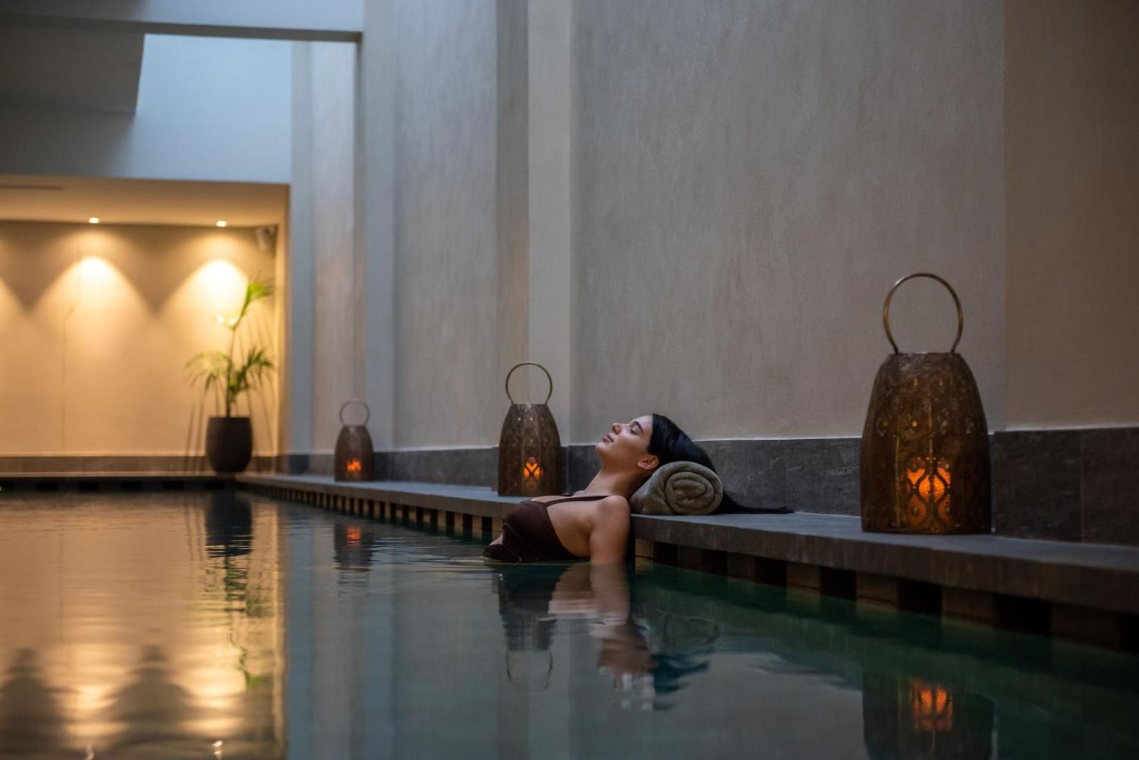 Sieviete relaksējas Cap St Georges Hotel & Resort spa zonā pie baseina ar dekoratīvām laternām un mierīgu apgaismojumu