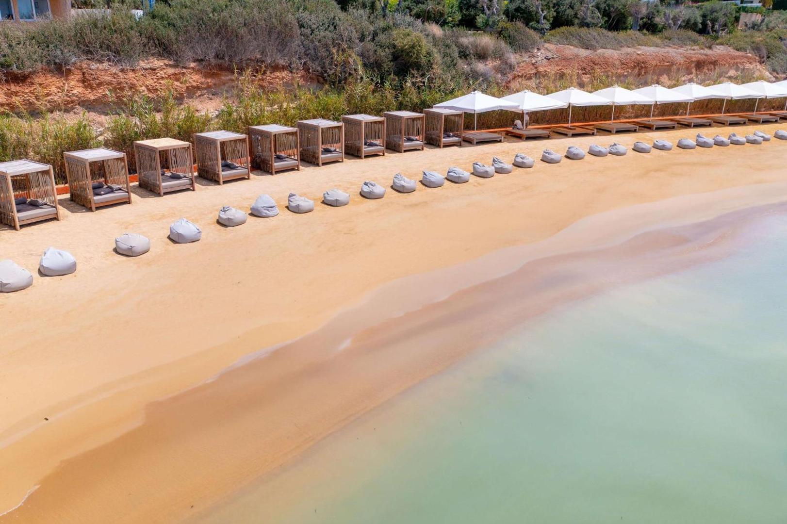Cap St Georges Hotel & Resort privātā pludmale ar saulessargiem, gultām un sēžammaisiem pie dzidra ūdens Kiprā