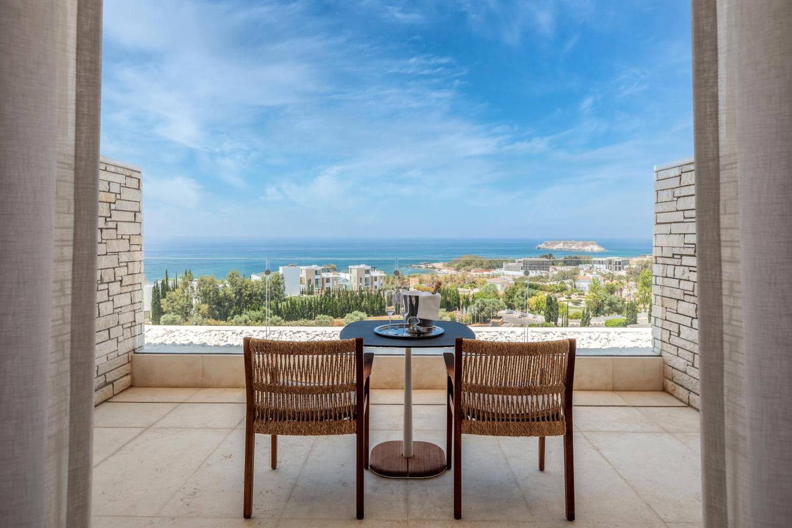 Privāts balkons Cap St Georges Hotel & Resort viesnīcā ar galdiņu diviem, dzērieniem un panorāmas skatu uz Pafas piekrasti