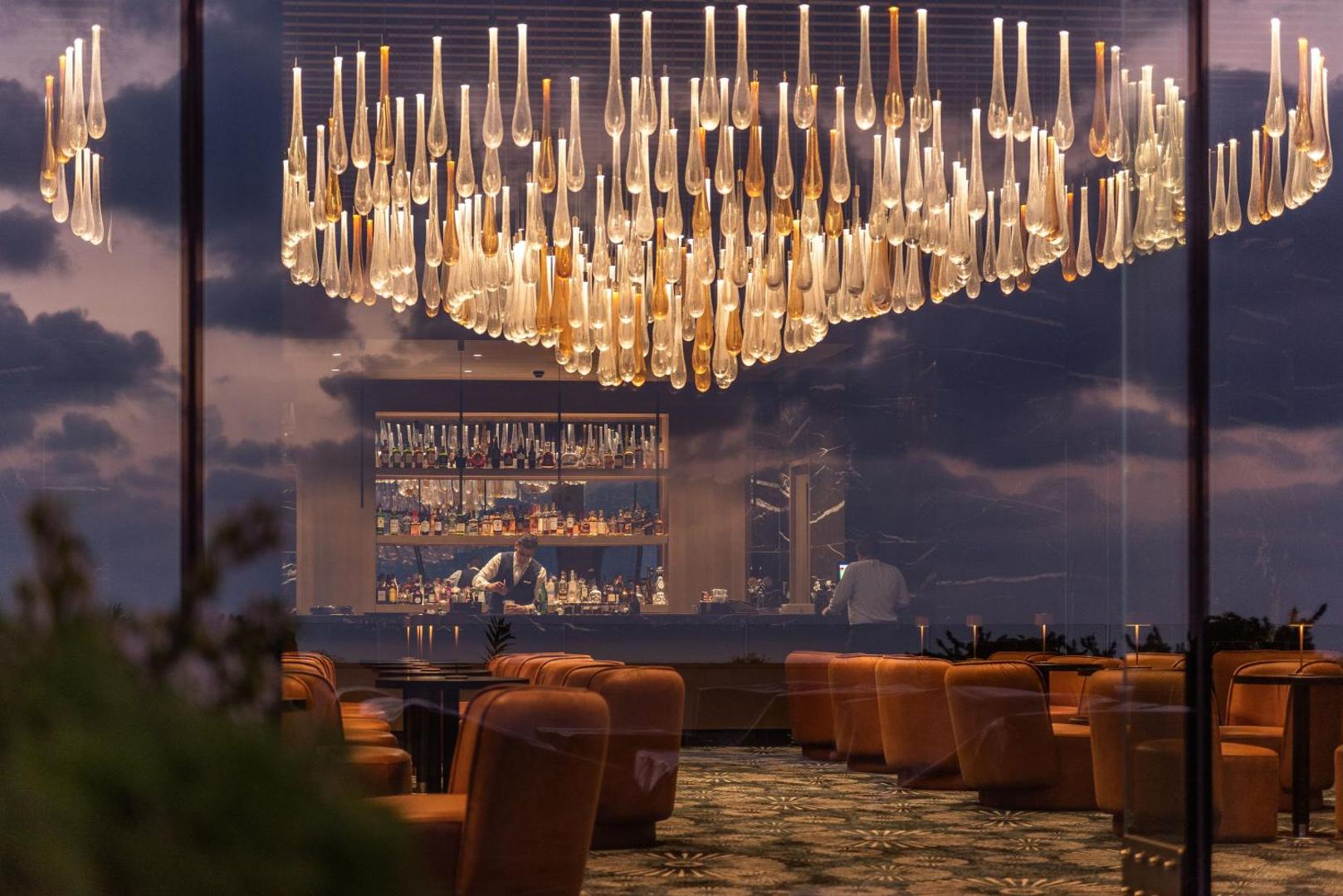 Elegants Cap St Georges Hotel & Resort lobby bārs ar iespaidīgu lustru un modernu interjeru vakara stundās