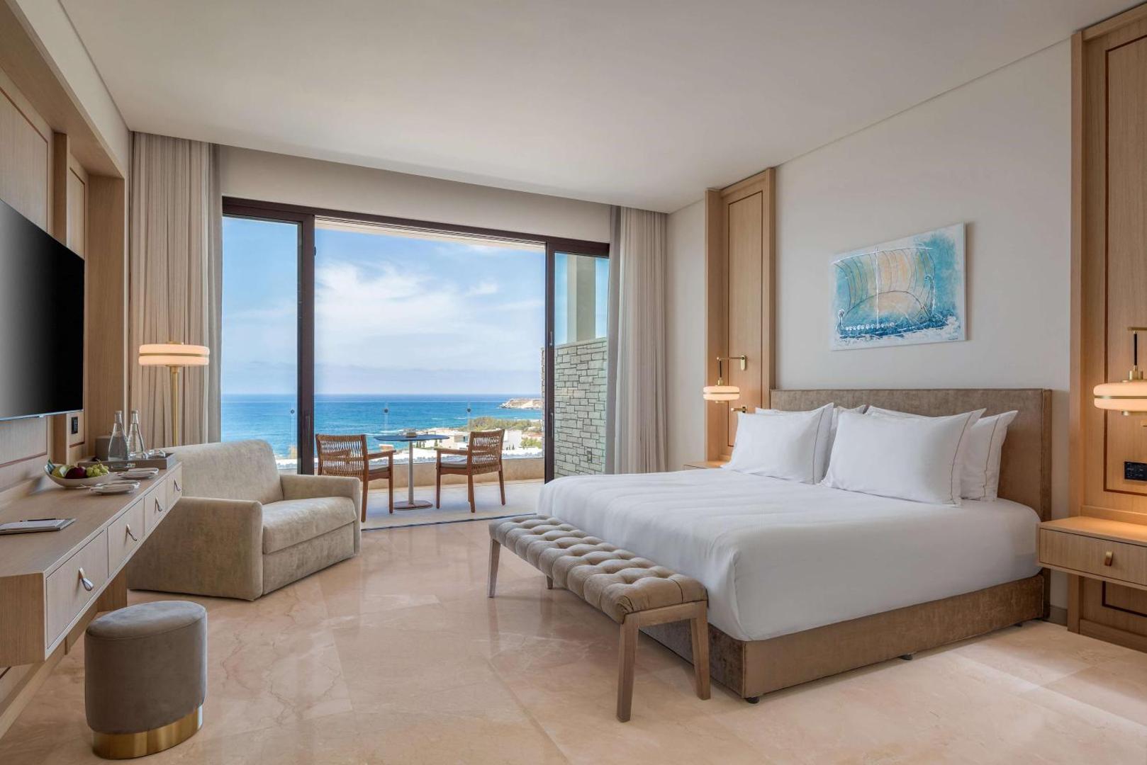 Cap St Georges Hotel & Resort gaišs numurs ar skatu uz jūru, lielu gultu, atpūtas zonu un privātu balkonu