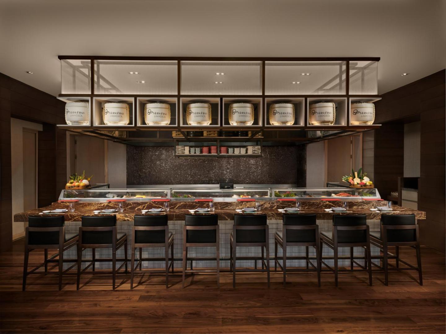 Amara Hotel Matsuhisa Limassol restorāna suši bārs ar tumša koka apdari, marmora leti un tradicionālām japāņu dekorācijām