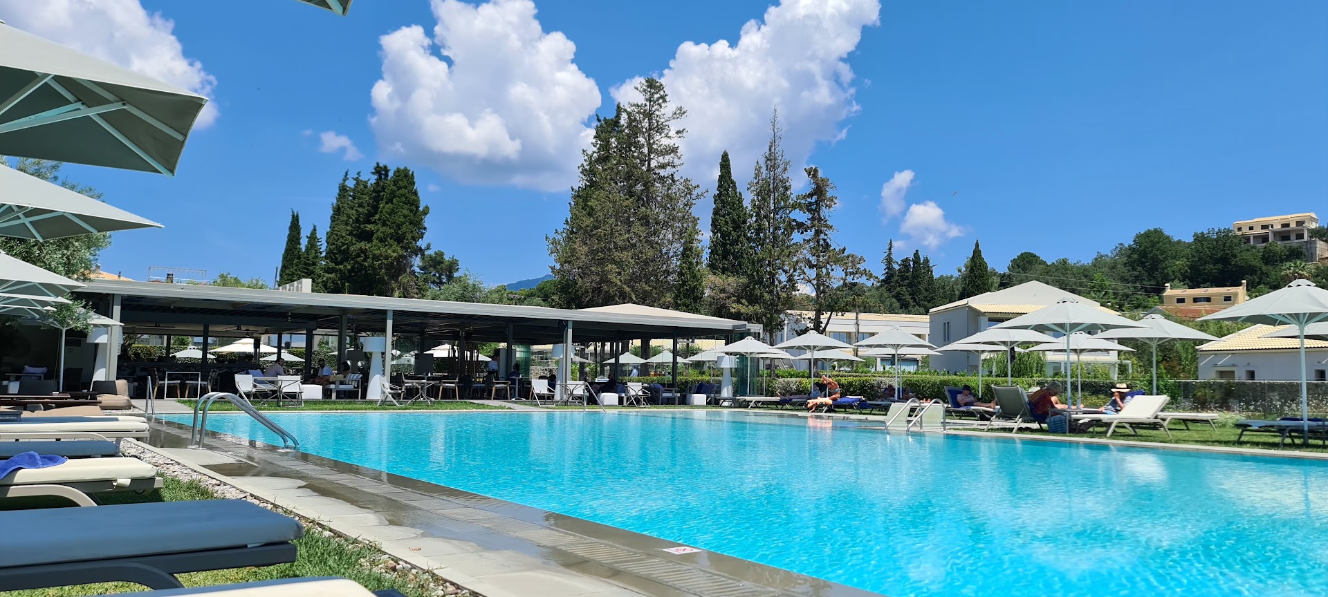 Rodostamo Hotel & Spa baseina zona ar blakus esošu restorānu un bāru zem nojumes, apkārtnē koki un saulessargi