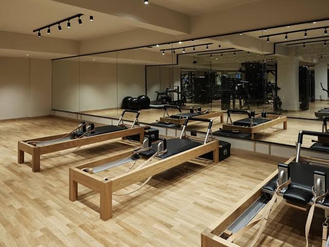 Stella Blue Seaside Resort fitnesa zāle ar modernām pilates reformatoru iekārtām un spoguļu sienu — gaiša telpa sporta nodarbībām