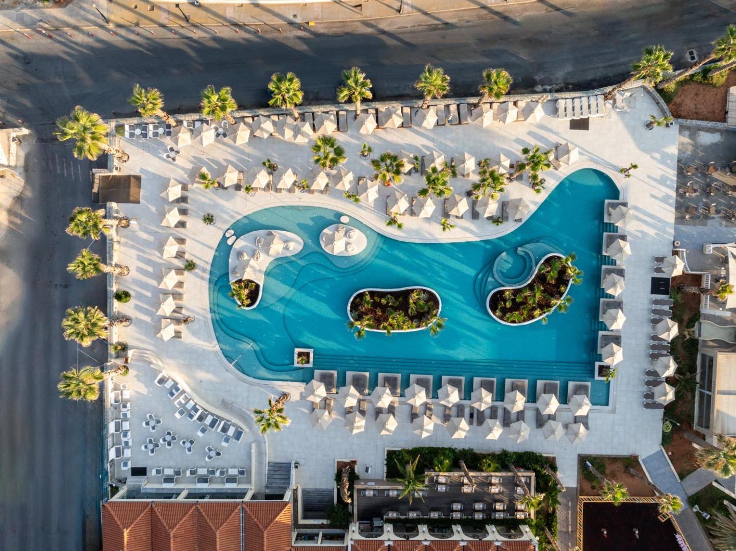 Stella Blue Seaside Resort skats no putna lidojuma uz lielo āra baseinu ar salām, palmām un atpūtas zonu Krētā