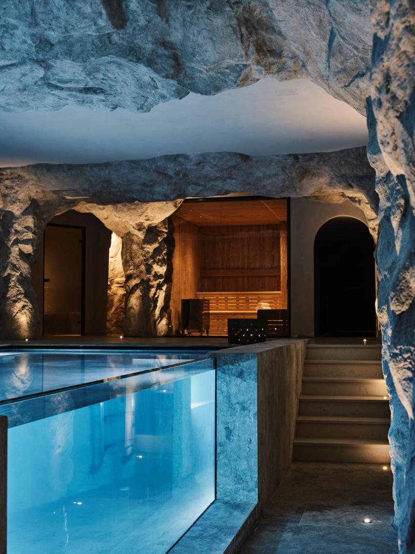 Stella Blue Seaside Resort unikāls iekštelpu baseins ar stikla sienu, kas integrēts dabīgā klinšu alā līdzās modernai pirtij.