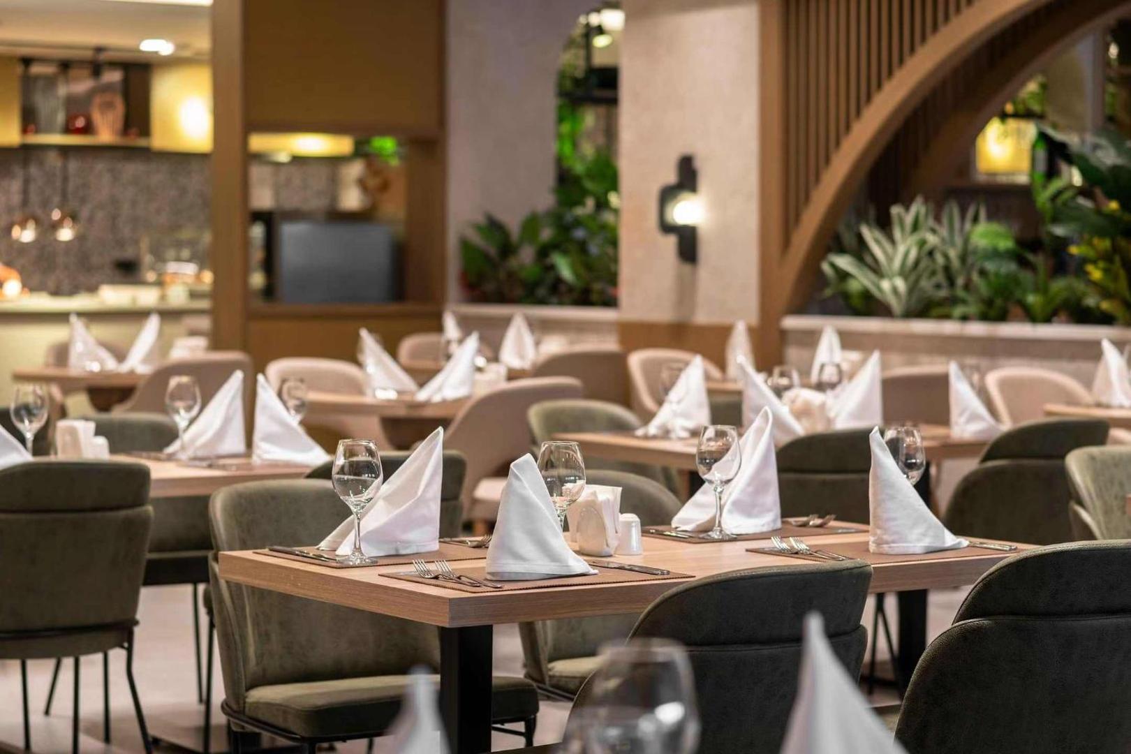 Tuvplāns uz eleganti klātiem galdiem Vox Maris Resort restorānā — balti salvetes un mirdzošas glāzes vakariņām