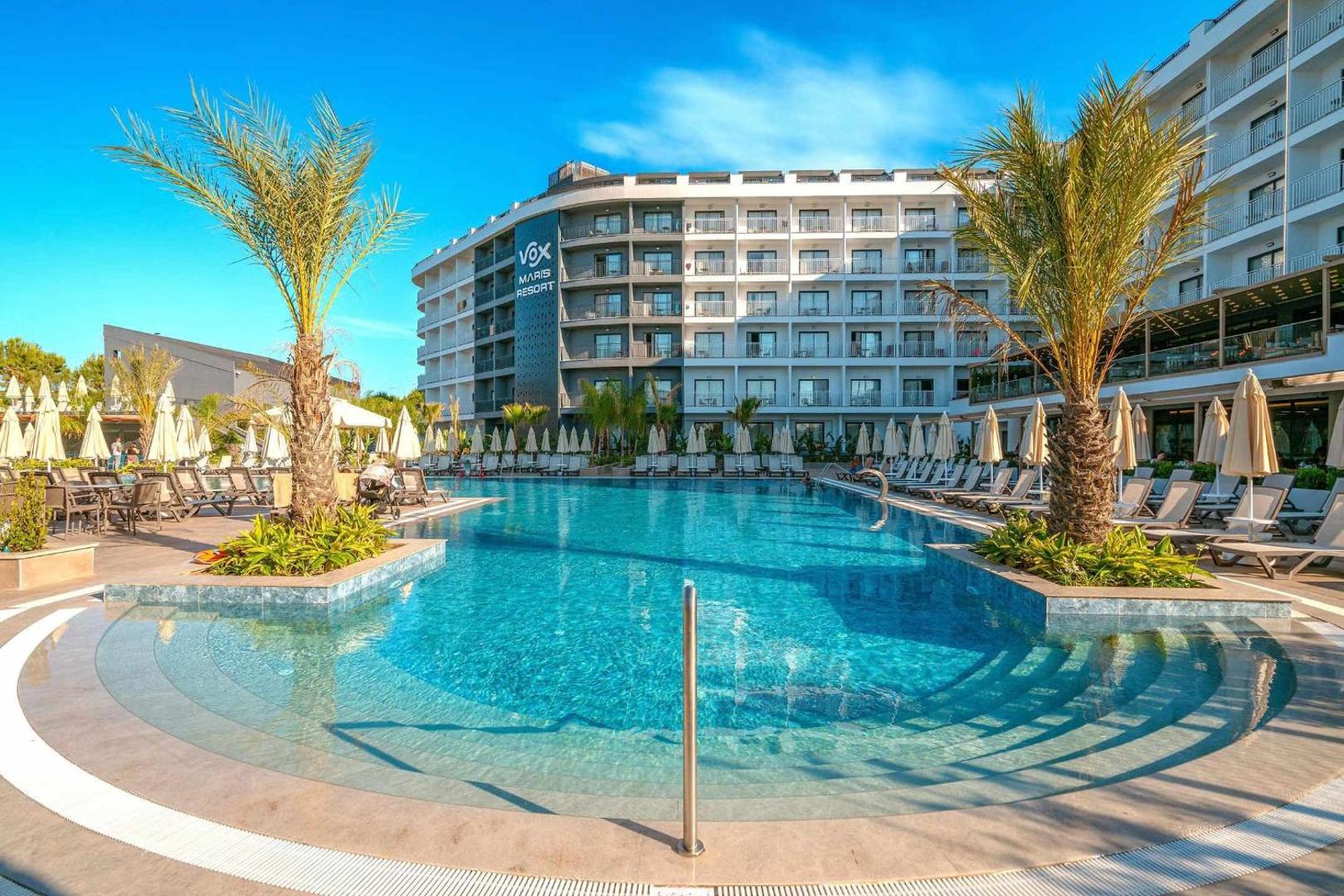 Vox Maris Resort galvenais āra baseins ar palmām un saulessargiem Sides reģionā, Turcijā — gaiša un plaša atpūtas zona