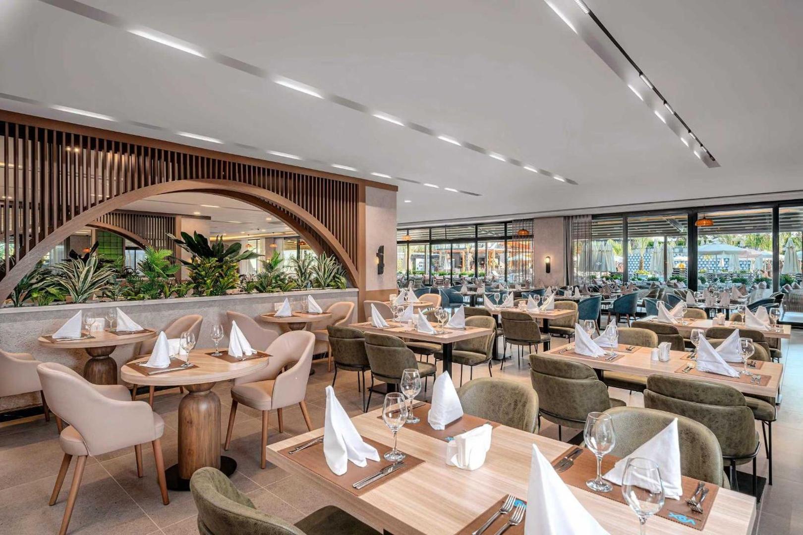 Vox Maris Resort galvenais restorāns ar modernu interjeru, koka elementiem un eleganti klātiem galdiem iekštelpās