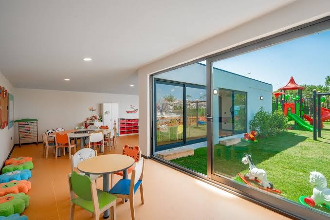 Vox Maris Resort bērnu klubs ar rotaļu zonu iekštelpās un āra rotaļu laukumu ar slidkalniņiem zaļā zālienā