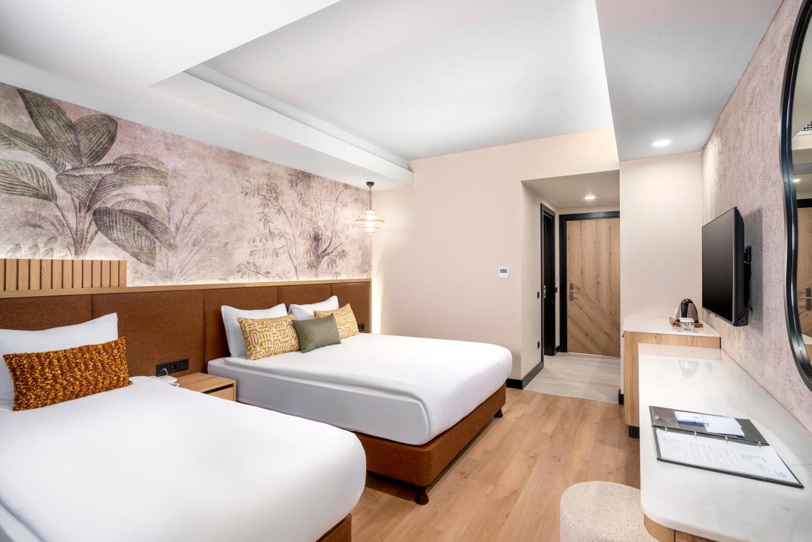 Vox Maris Resort moderns numurs ar divām gultām, gaišu interjeru un dekoratīvām tapetēm — mājīga naktsmītne Turcijā