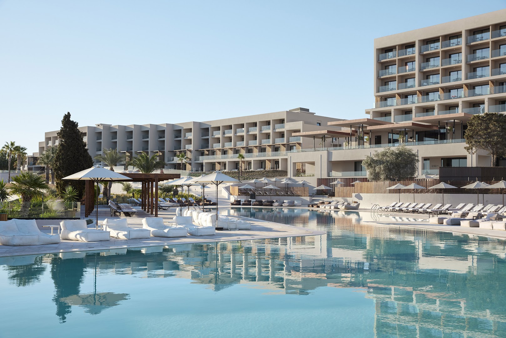 Helea Lifestyle Beach Resort modernā arhitektūra un plašais galvenais baseins ar atpūtas krēsliem un saulessargiem