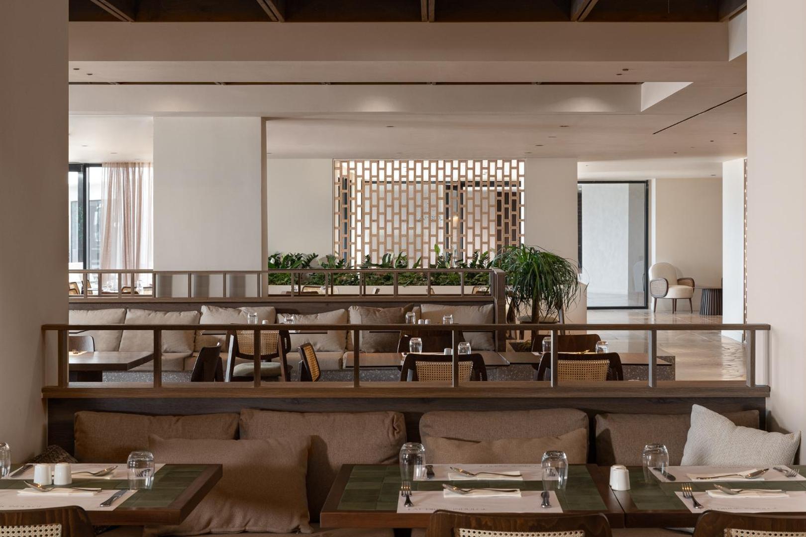 Helea Lifestyle Beach Resort restorāna iekštelpas ar mīkstiem dīvāniem, koka apdari un eleganti klātiem galdiem vakariņām