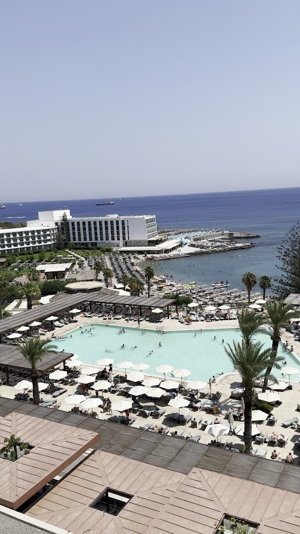 Skats no augšas uz Helea Lifestyle Beach Resort baseinu, pludmales zonu un zilo jūru ar kuģiem horizontā Rodas piekrastē