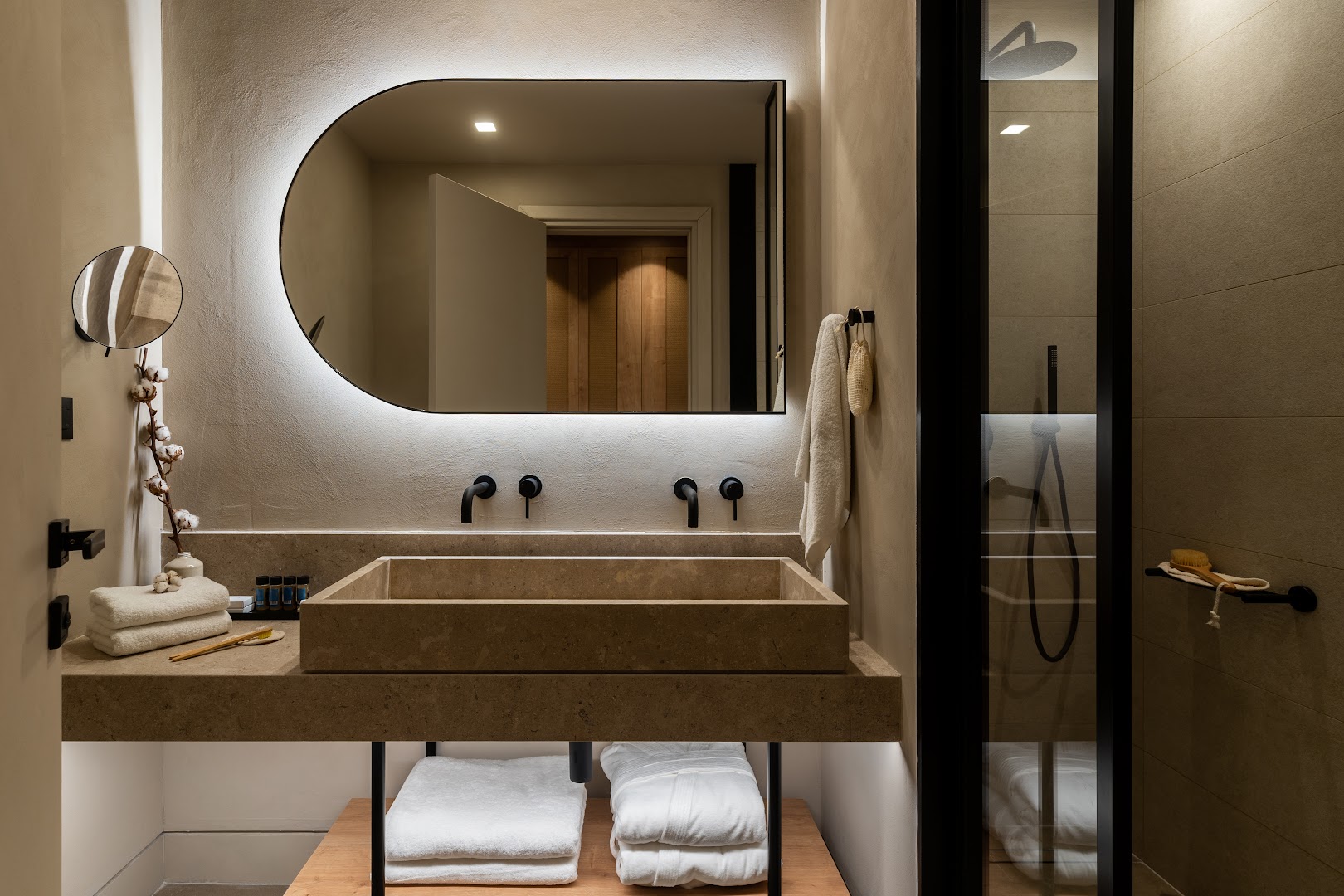 Helea Lifestyle Beach Resort numura vannasistaba ar akmens izlietni, modernu spoguli un dušas zonu siltos toņos