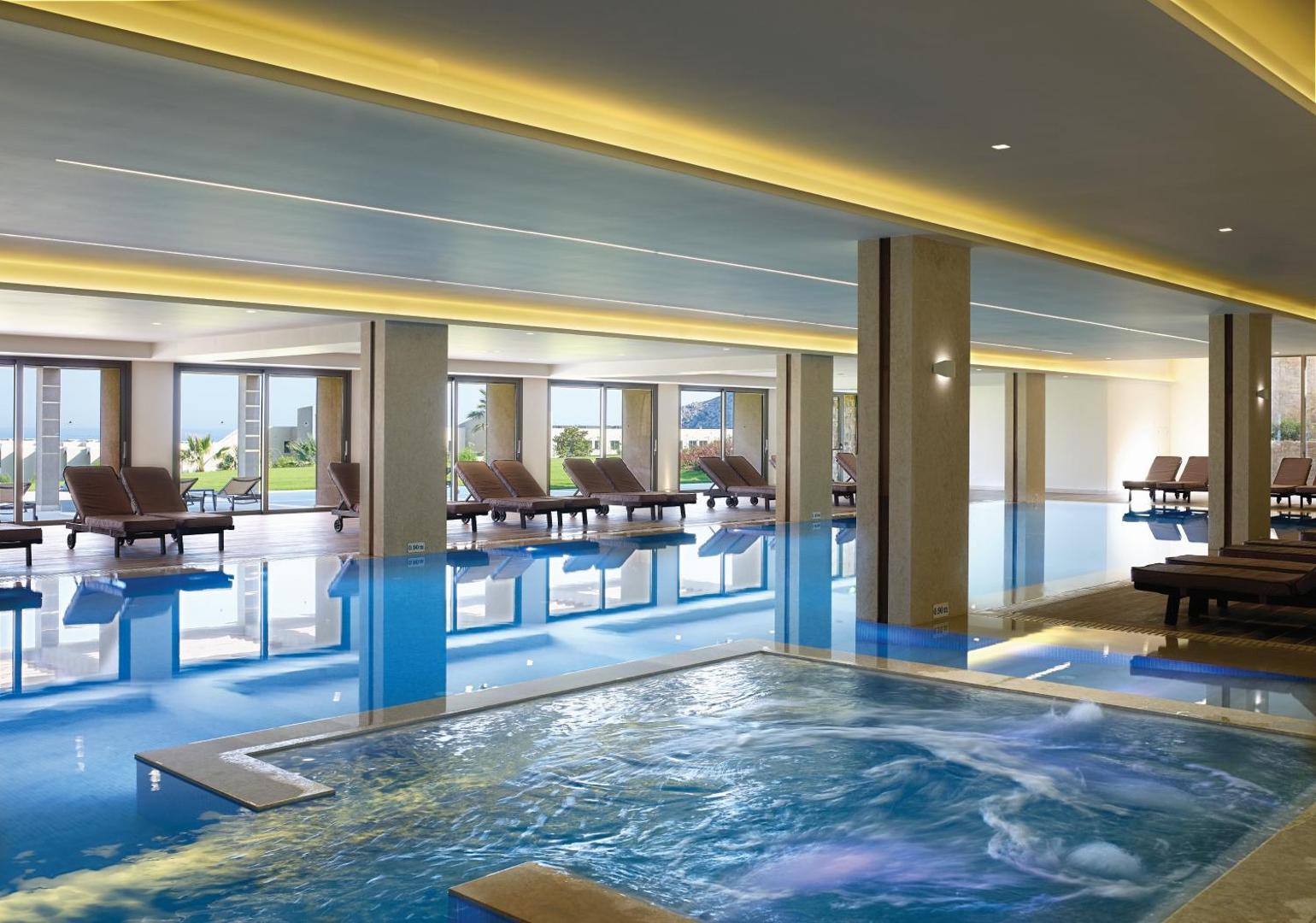 Atlantica Imperial Resort iekštelpu spa baseins ar hidromasāžas zonu un atpūtas krēsliem — moderna relaksācijas zona ar panorāmas logiem