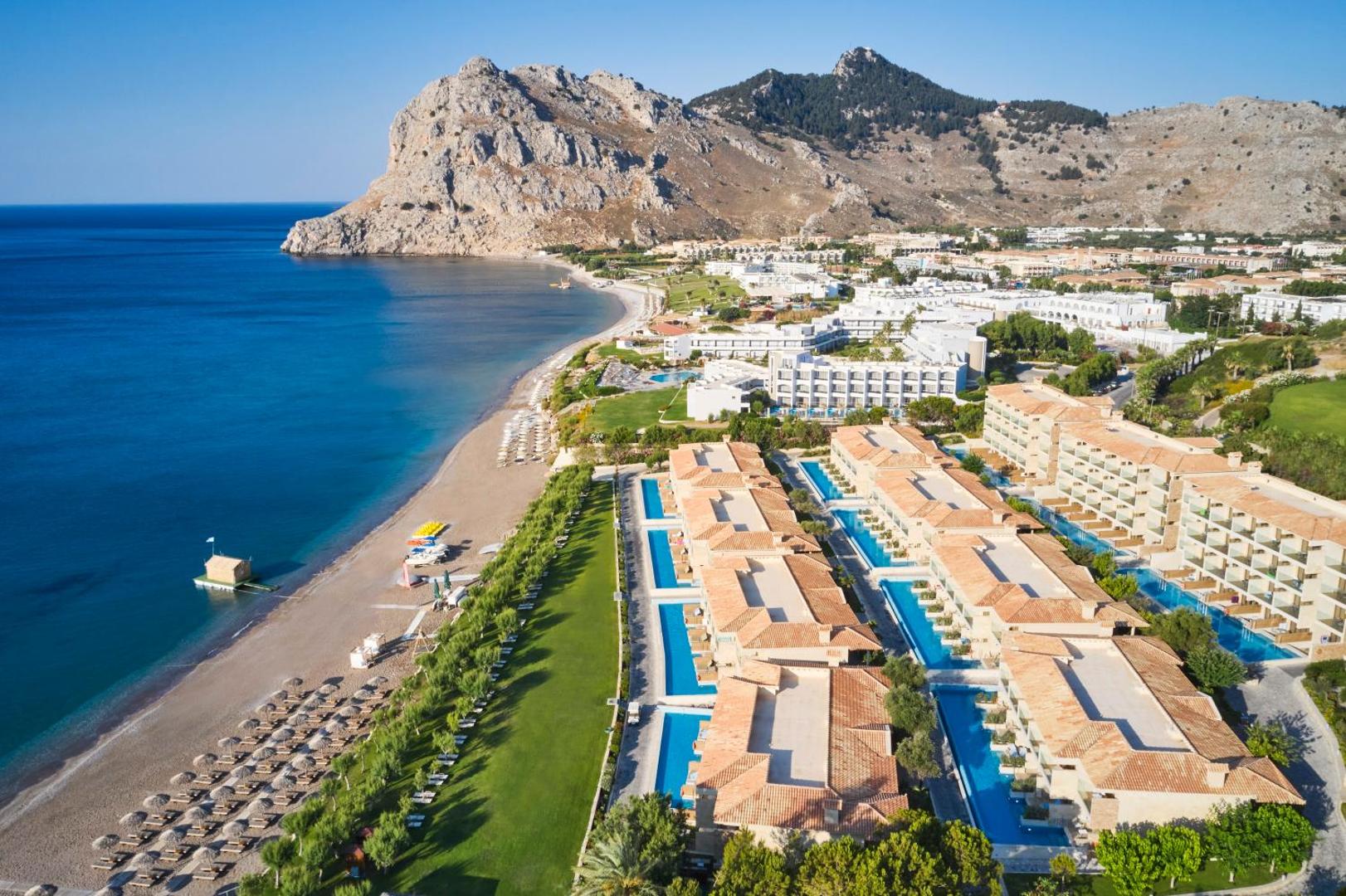 Atlantica Imperial Resort panorāmas skats uz viesnīcas korpusiem, peldbaseiniem un Rodas kalnu ainavu pie Vidusjūras krasta