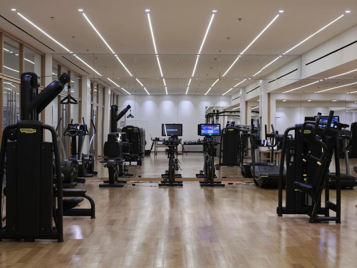 Atlantica Imperial Resort moderns fitness centrs ar Technogym aprīkojumu, spoguļsienu un gaišu koka grīdu Rodas viesnīcā