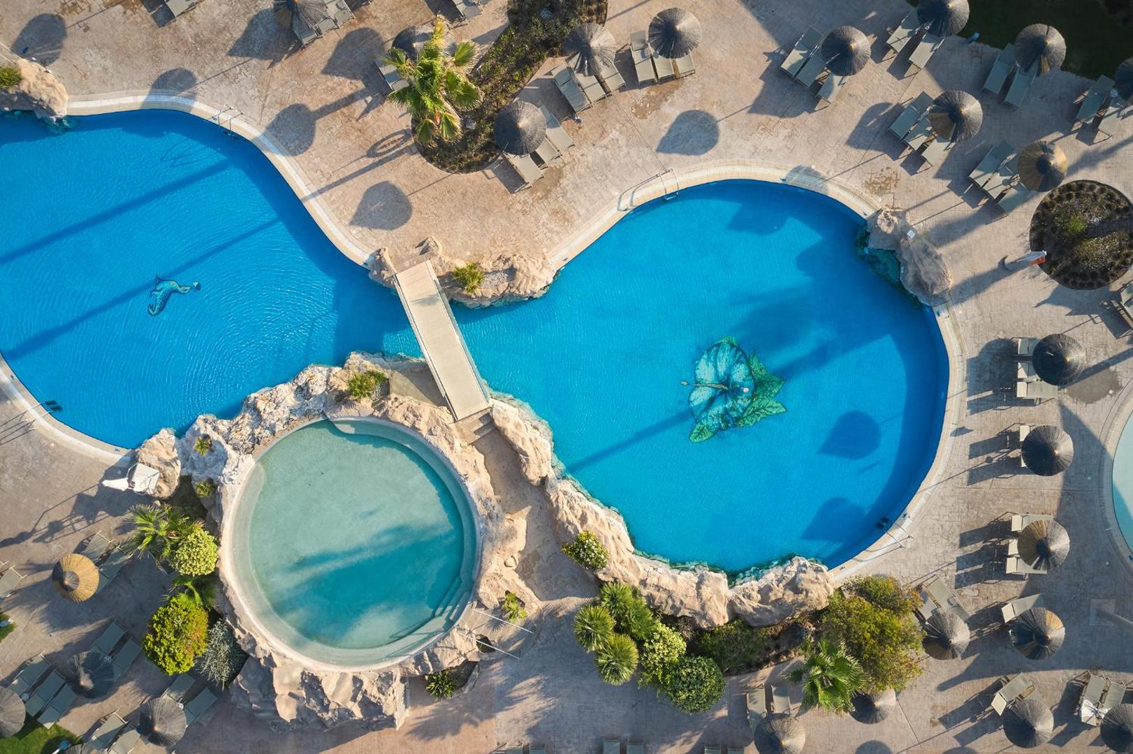 Atlantica Aegean Blue baseinu komplekss no putna lidojuma — dažādu formu baseini, tiltiņi un atpūtas krēsli