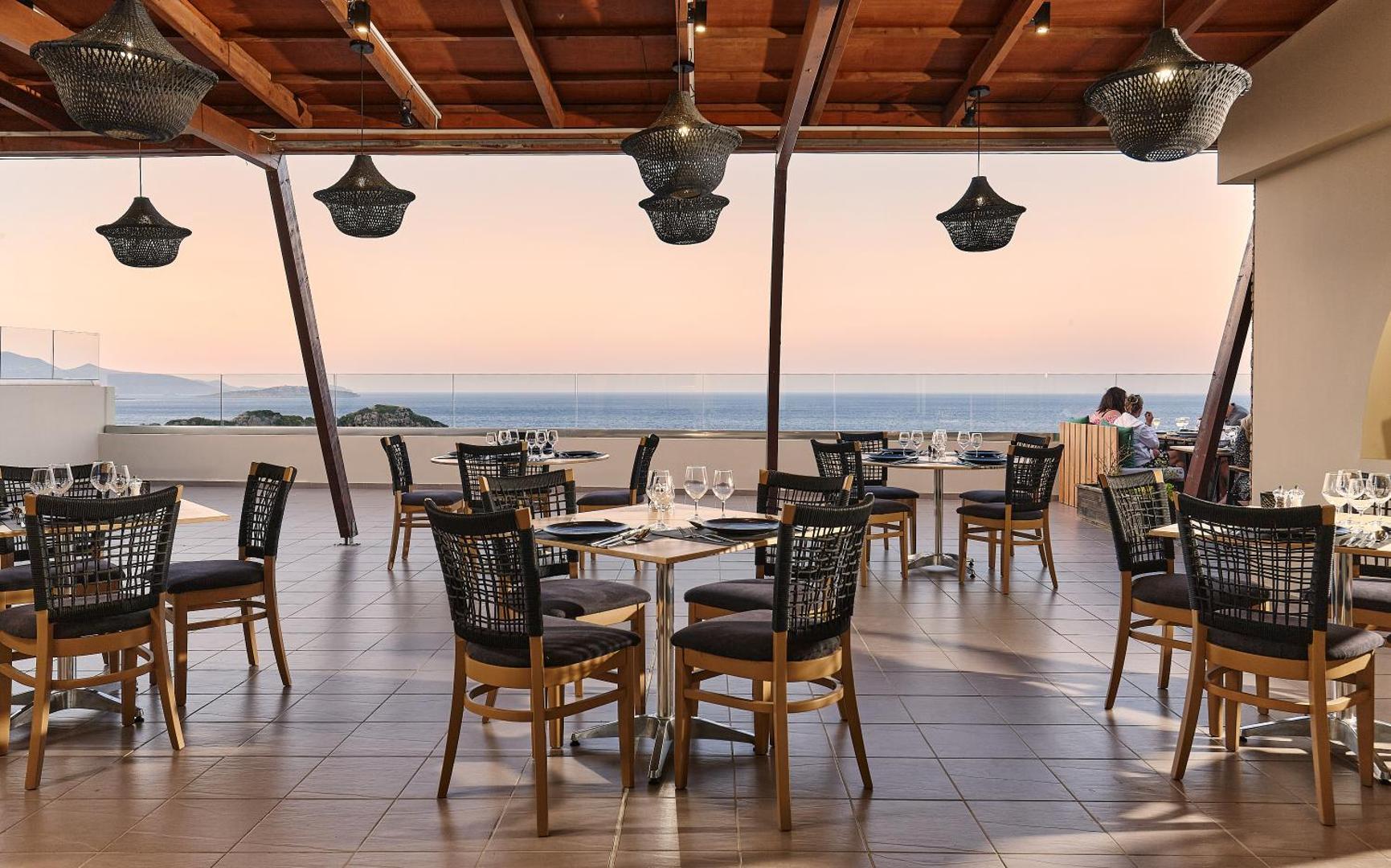 Blue Marine Resort & Spa terases restorāns saulrieta laikā — elegants interjers ar pītiem gaismekļiem un skatu uz horizontu