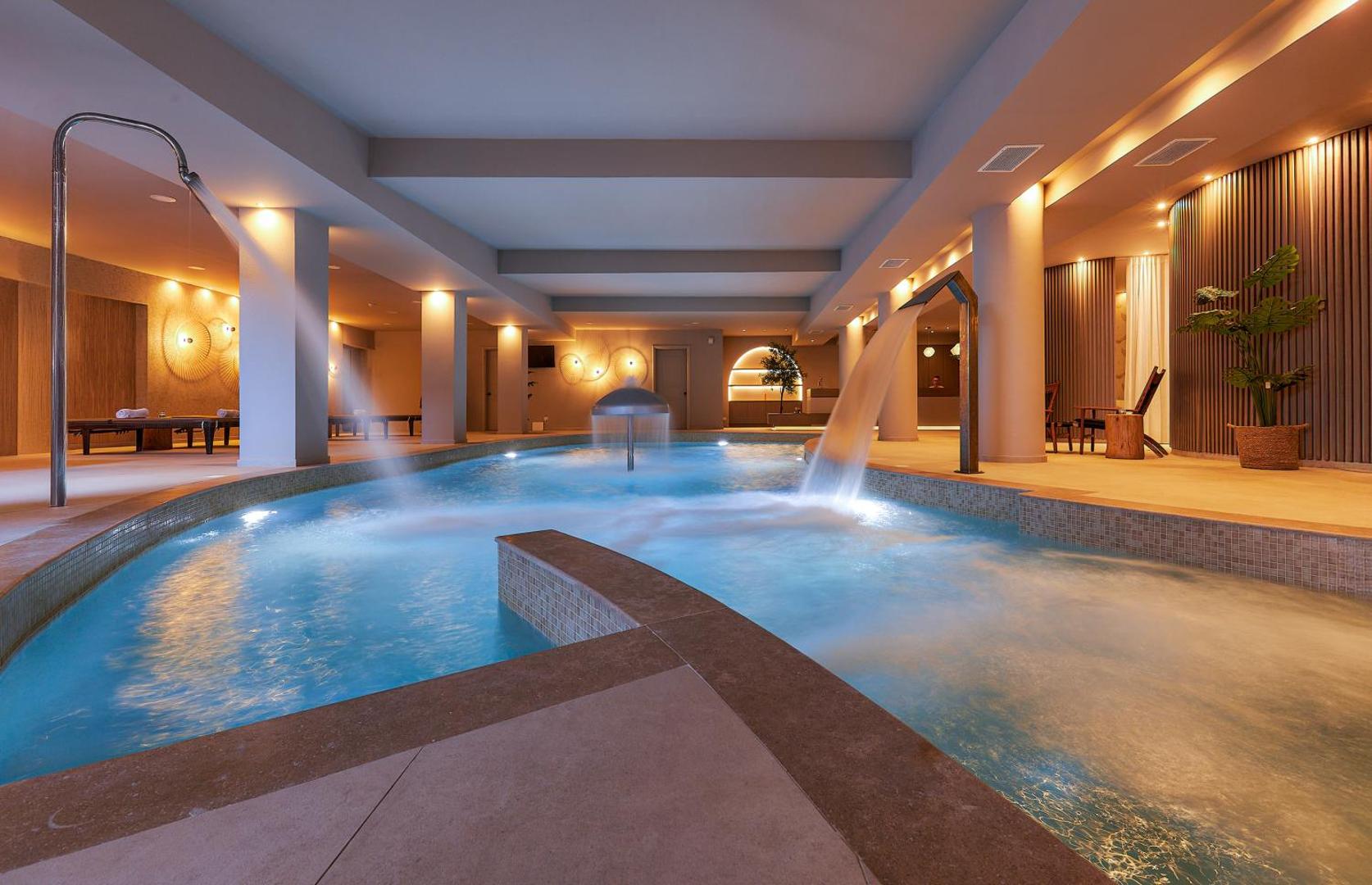 Blue Marine Resort & Spa iekštelpu spa baseins ar kaskādes masāžas strūklām un siltu, relaksējošu apgaismojumu