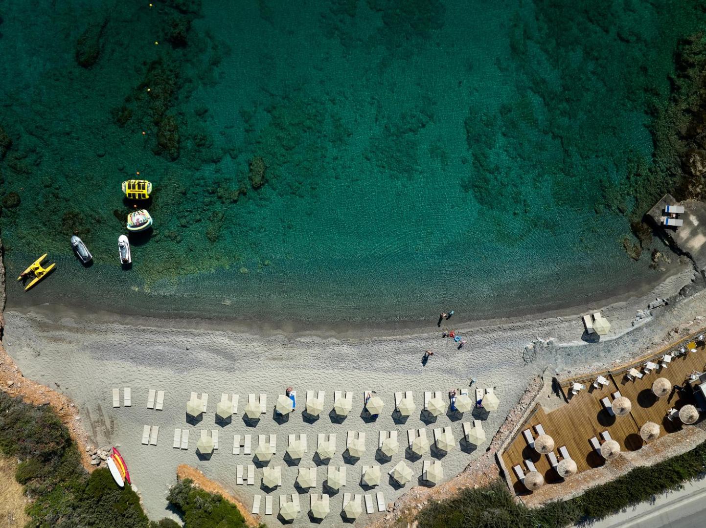 Aerofoto ar Blue Marine Resort & Spa pludmales zonu — tirkīza jūra, smilšu krasts ar saulessargiem un ūdens sporta inventārs