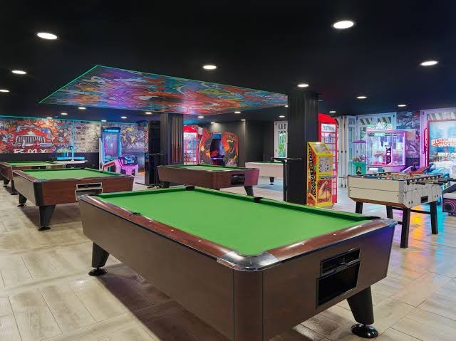 Gran Oasis Resort spēļu telpa ar biljarda galdiem, galda futbolu un spēļu automātiem — moderna atpūtas zona iekštelpās