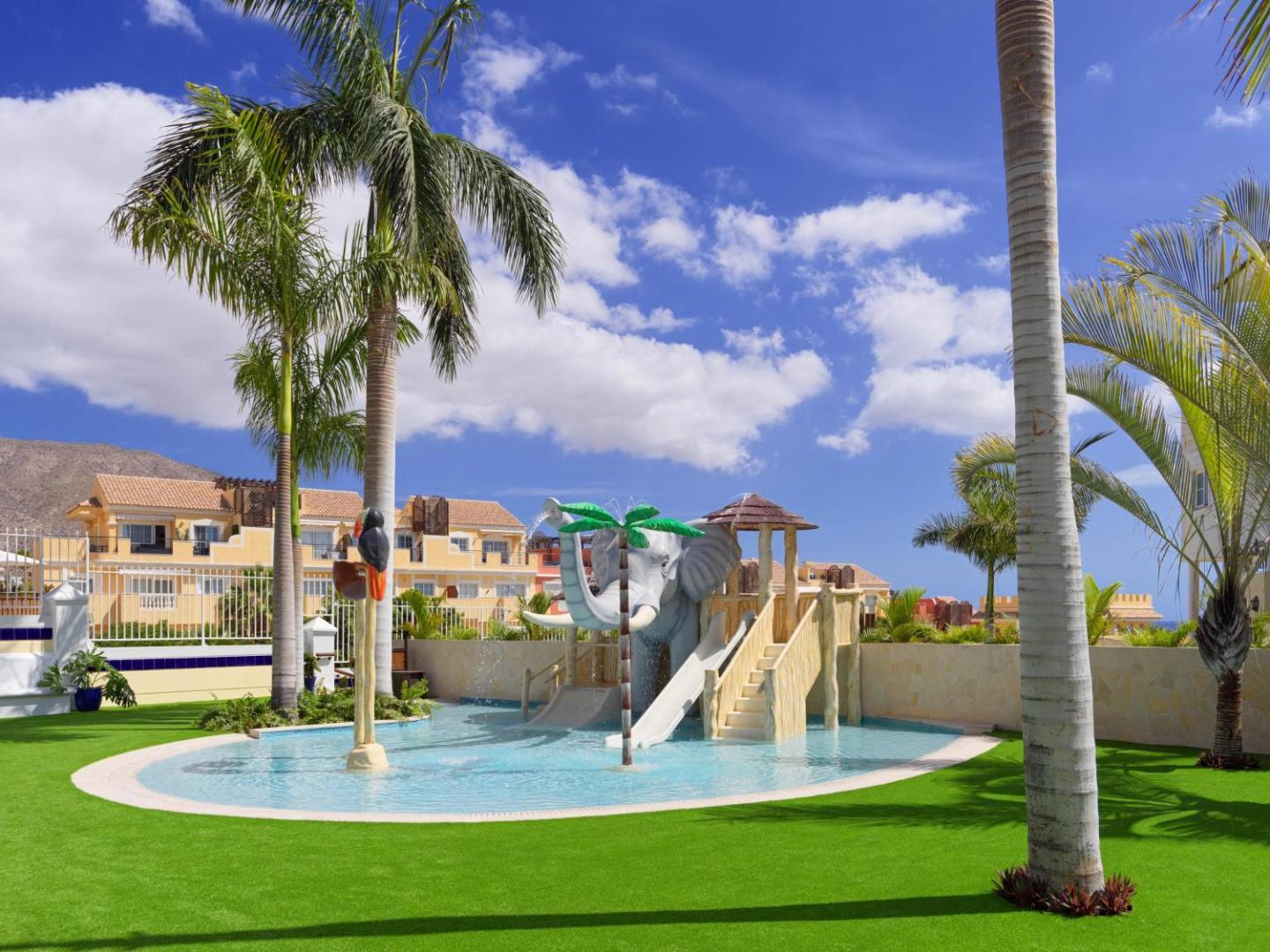 Gran Oasis Resort bērnu ūdens atrakciju zona ar ziloņa figūru un slidkalniņiem Tenerifē — plašs skats uz viesnīcas teritoriju un palmām