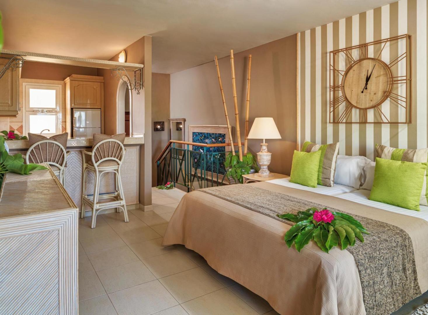 Gran Oasis Resort studijas tipa numurs ar gultu, virtuves zonu, bāra krēsliem un dekoratīviem elementiem siltos toņos