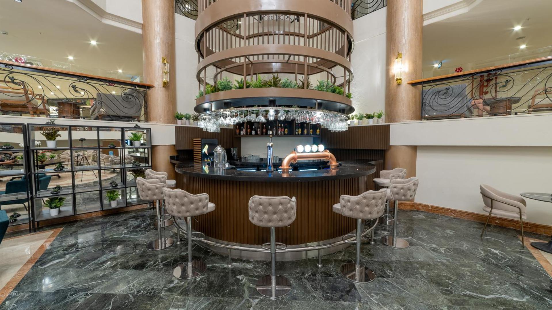 Numa Club Side viesnīcas lobby bārs ar modernu apļveida leti, bāra krēsliem un dekoratīviem apstādījumiem Side reģionā, Turcijā