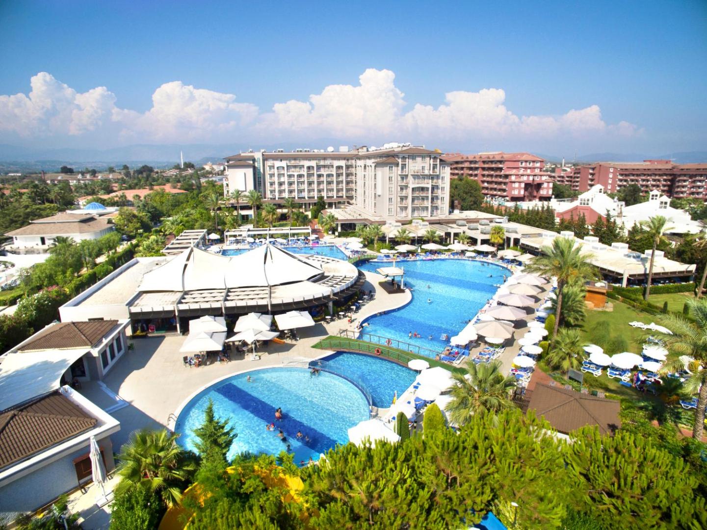Sunis Elita Beach Resort Hotel & SPA teritorijas skats no augšas ar baseiniem, saulessargiem un zaļo zonu