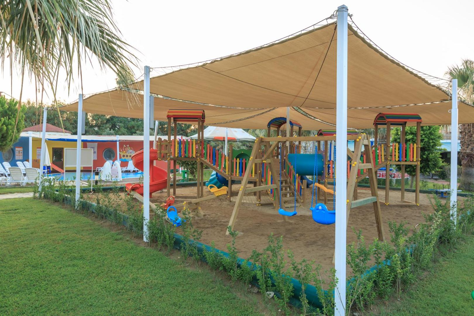 Sunis Elita Beach Resort bērnu rotaļu laukums ar nojumi un dažādām atrakcijām smiltīs — droša izklaides zona ģimenēm ar bērniem