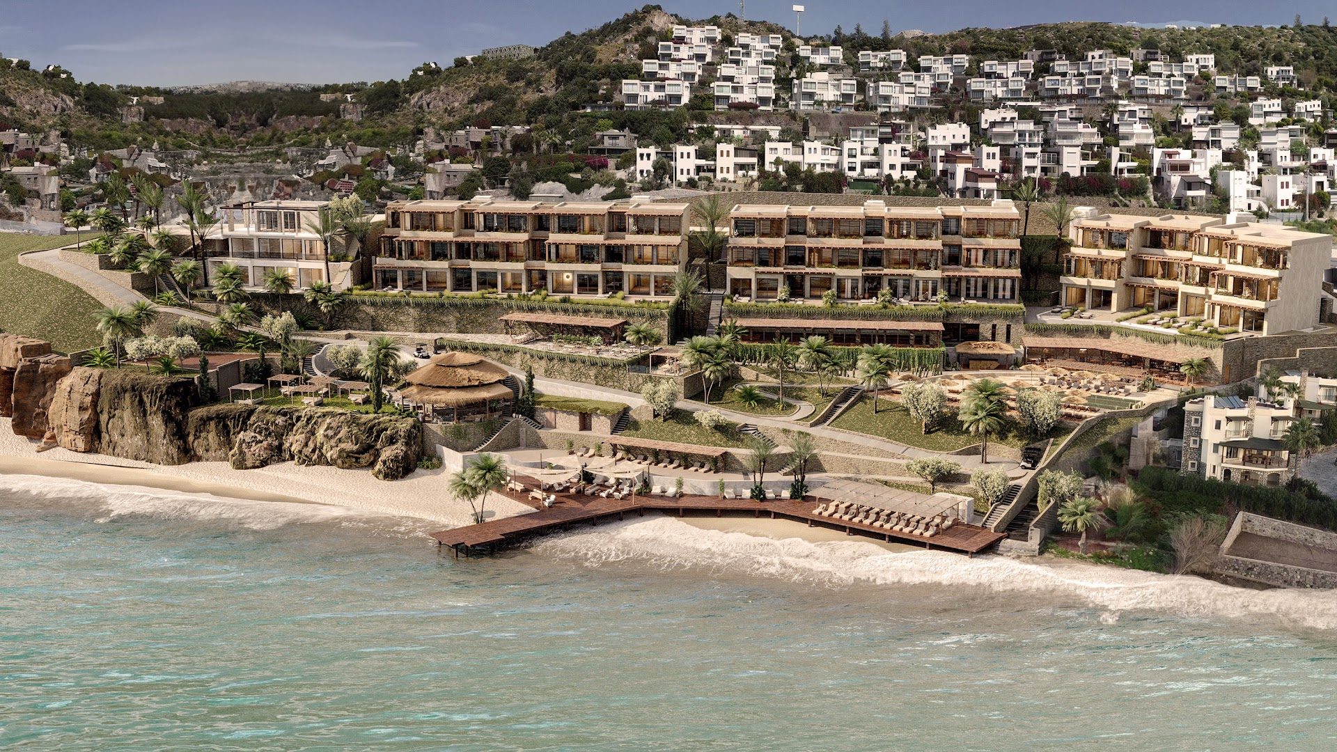 OKU Bodrum viesnīcas kompleksa panorāmas skats Bodrumas piekrastē ar pludmali, koka piestātni un modernām ēkām kalna nogāzē