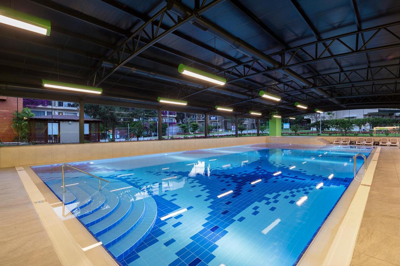 Pine Beach Belek iekštelpu baseins ar modernu apgaismojumu, flīžu mozaīku un ērtām kāpnēm iekāpšanai