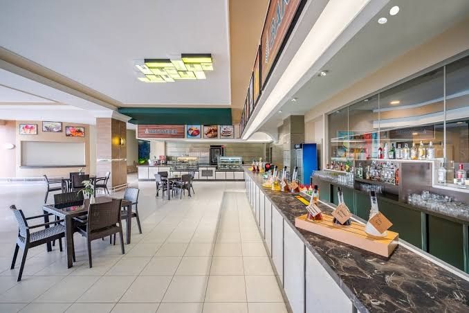 Pine Beach Belek plašais iekštelpu bārs un atpūtas zona ar modernu apgaismojumu, marmora leti un ērtiem krēsliem